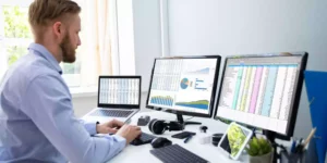 man working in excel spreadsheet with dual monitors